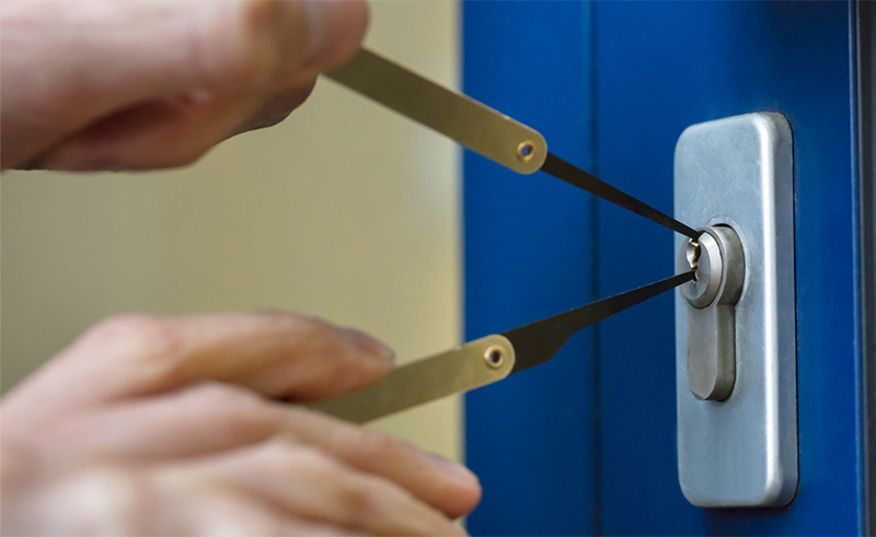 locksmith picking a silver covered lock on a blue door for a homeowner